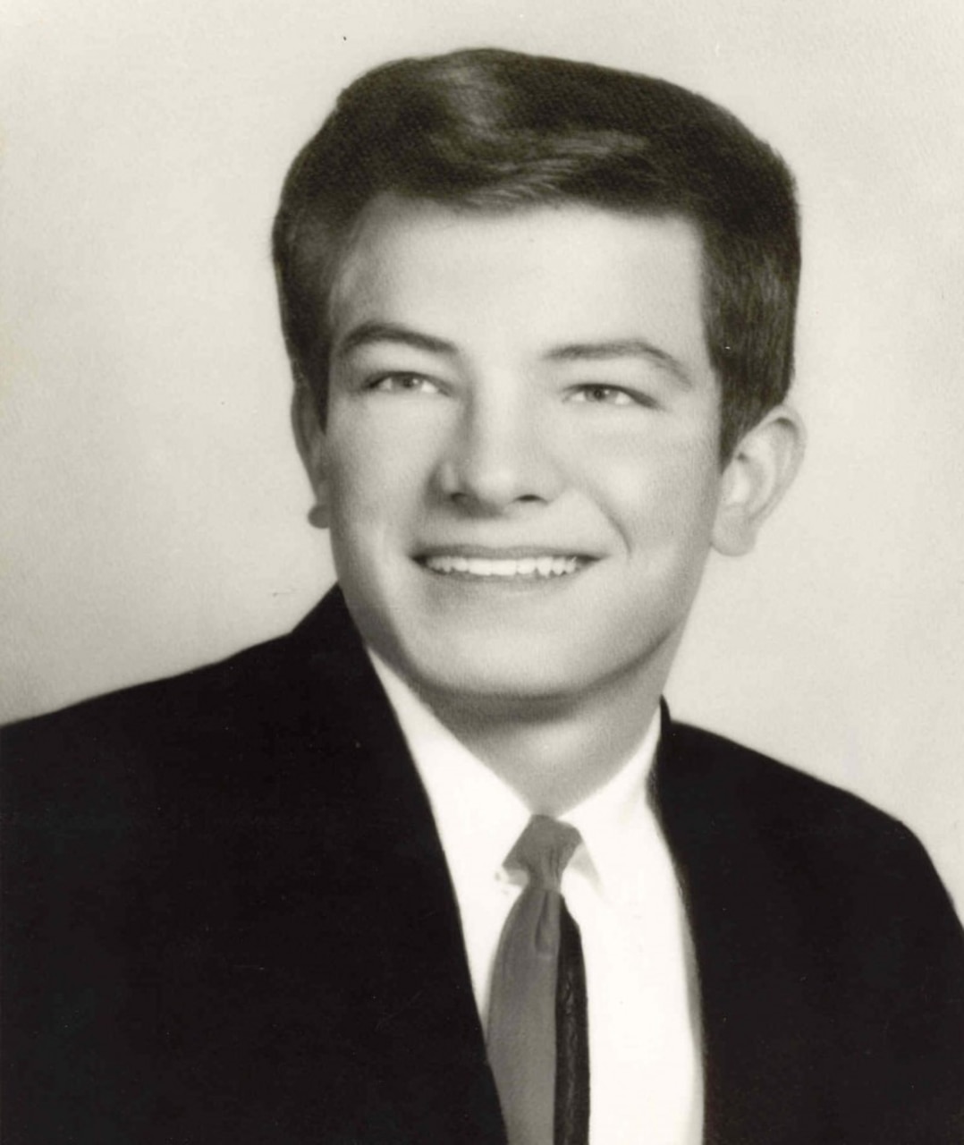 A young man wearing a suit and tie poses for a photo.