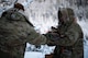 A U.S. Air Force Arctic Survival Training student hands a pile of firewood to a Survival, Evasion, Resistance and Escape specialist assigned to the Arctic Survival Training School during a recovery exercise on Eielson Air Force Base, Alaska, Nov. 18, 2021.