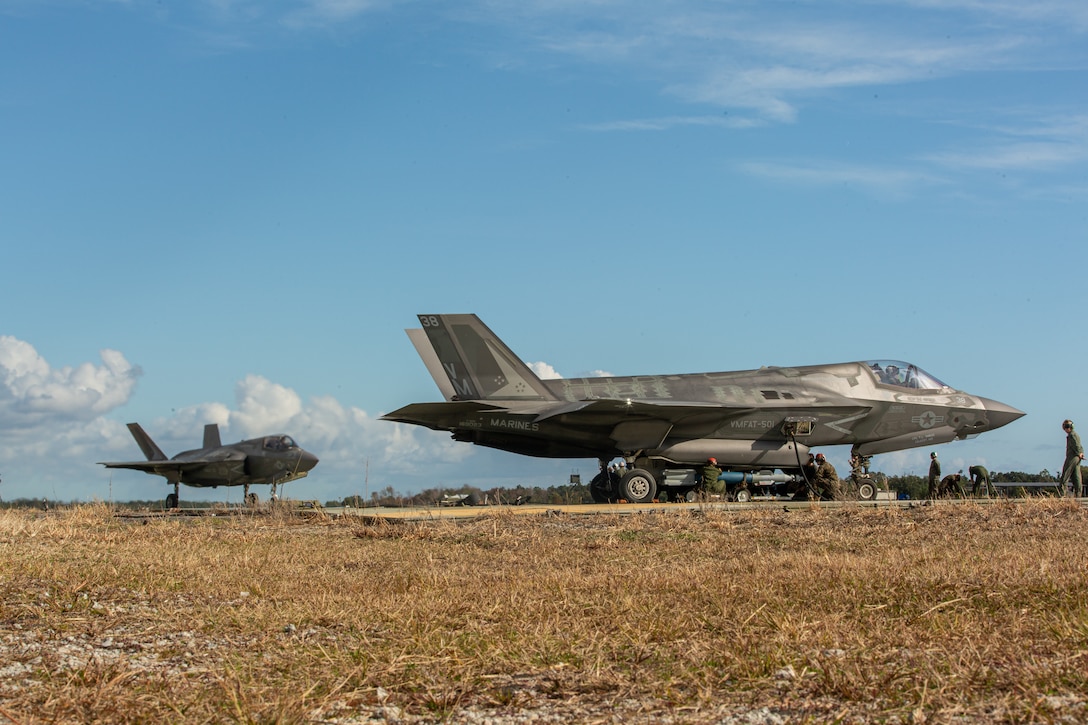 U.S. Marines with Marine Aviation Logistics Squadron (MALS) 31 and Marine Aerial Refueler Transport Squadron (VMGR) 252 refuel and arm two F-35B Lightning II assigned to Marine Fighter Attack Training Squadron (VMFAT) 501 at Marine Corps Auxiliary Landing Field (MCALF) Bogue, North Carolina, Nov. 18, 2021. The event was a demonstration of expeditionary advanced base operations (EABO) concepts to illustrate the capabilities of 2nd Marine Aircraft Wing as a result of the Commandant of the Marine Corps' force design. The demonstration marks the first time East Coast F-35 air delivery ground refueling and other F-35 operations have been conducted at MCALF Bogue. (U.S. Marine Corps photo by Chief Warrant Officer Bryan Nygaard)