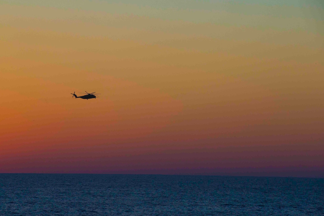 A helicopter flies over water.