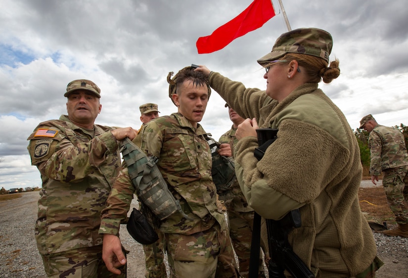 U.S. Army Spc. John Drake is assisted by Command Sgt. Maj. David Page and another Kentucky National Guard member after completing a 12 mile ruck march at Wendell H. Ford Regional Training Center in Greenville, Ky. on November 12th, 2021.  This photograph will be used in a visual history by the Kentucky Documentary Photographic Project to document Kentuckians through the years (Photograph by James R. Southard, Kentucky Documentary Photographic Project).