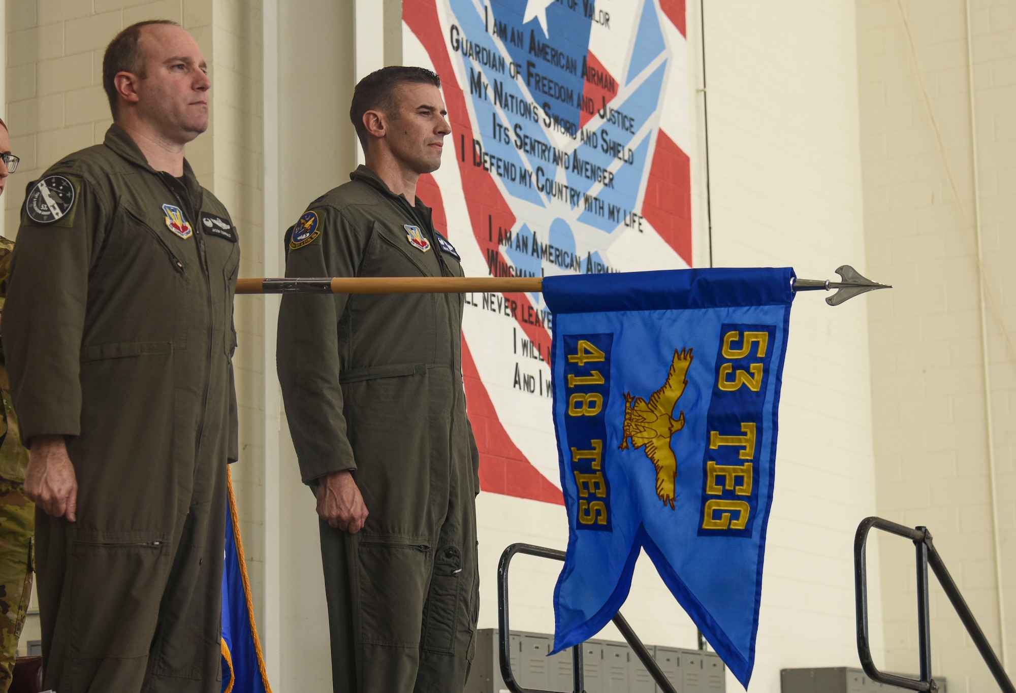 Pictured above are two Airmen standing at attention with a flag in between them.