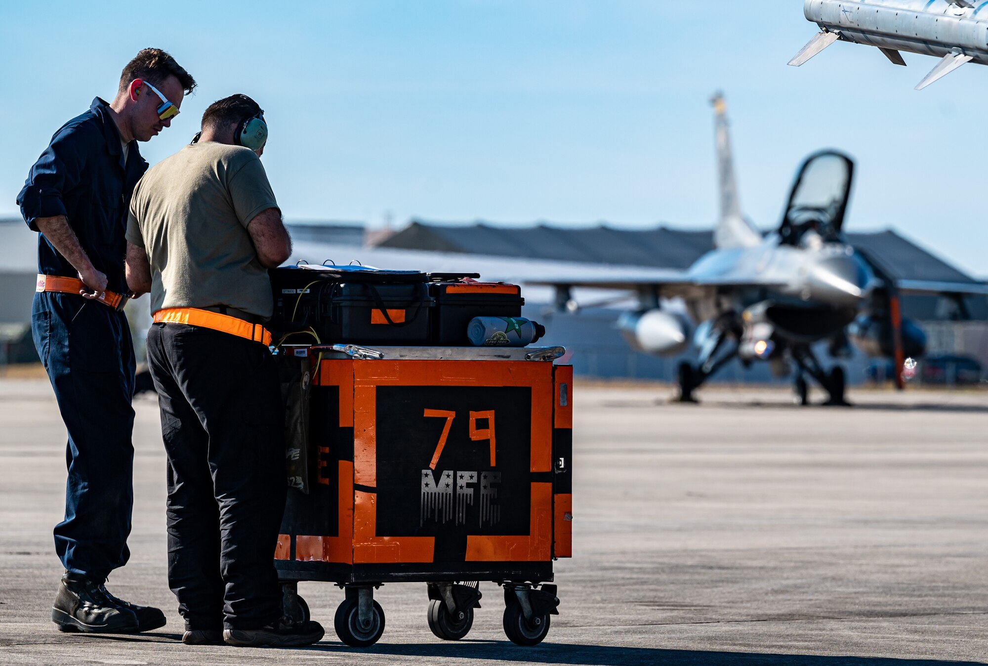 A pilot performing F-16 preflight checks.
