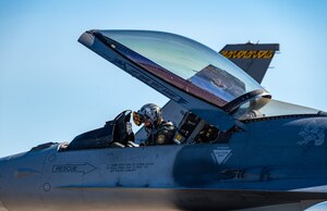 A pilot performing F-16 preflight checks.