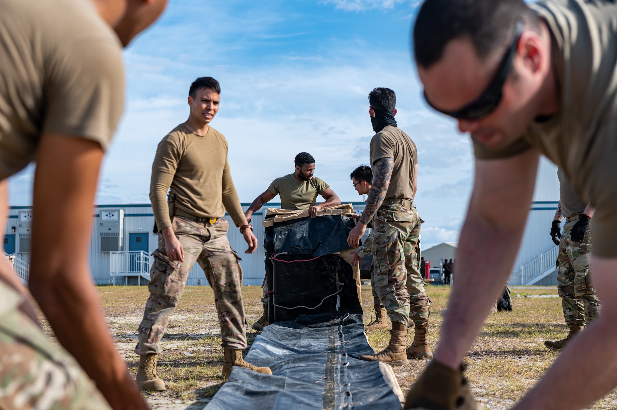 U.S. Airmen rolling up a tent.