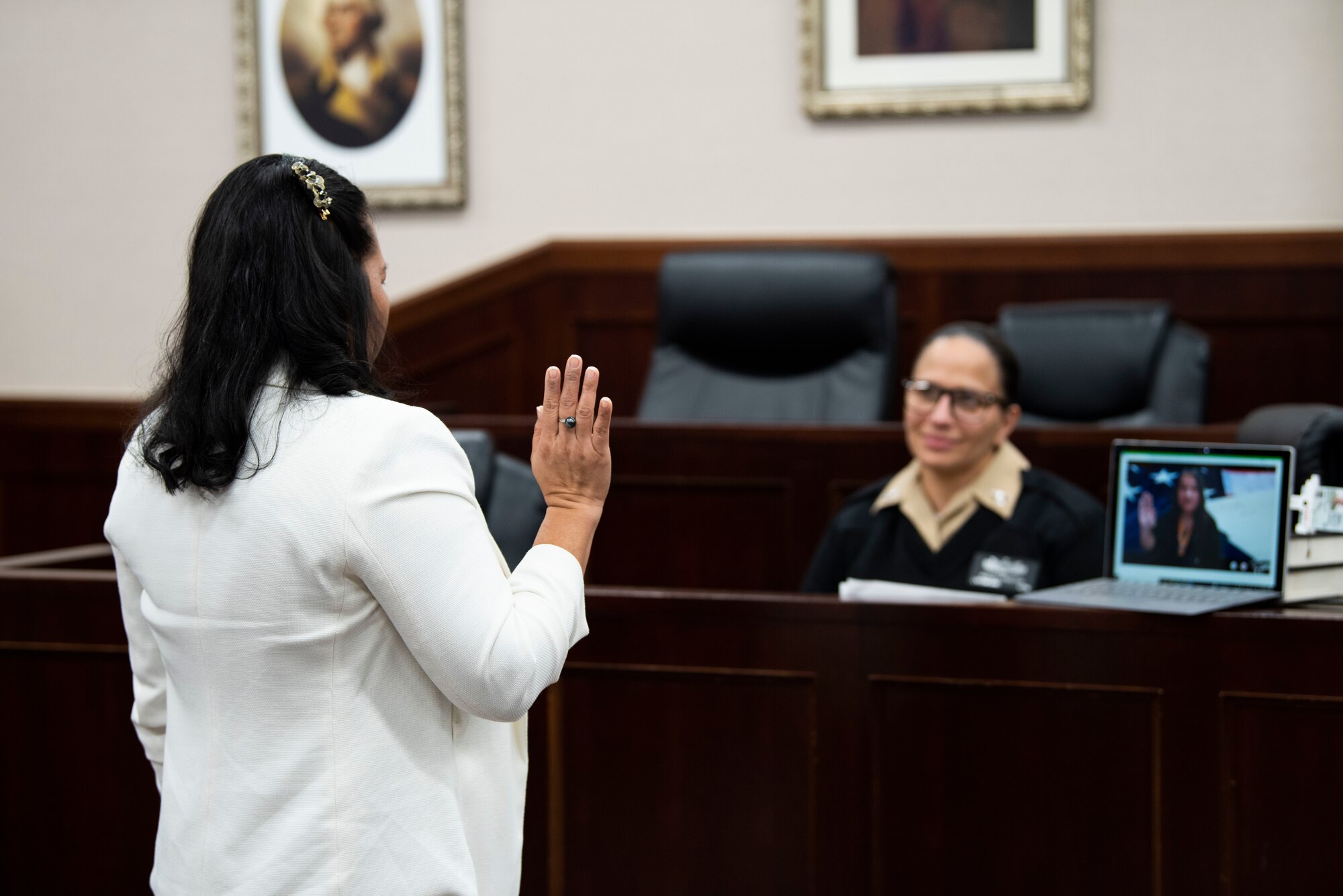 Female member raises right hand and says an oath to a laptop