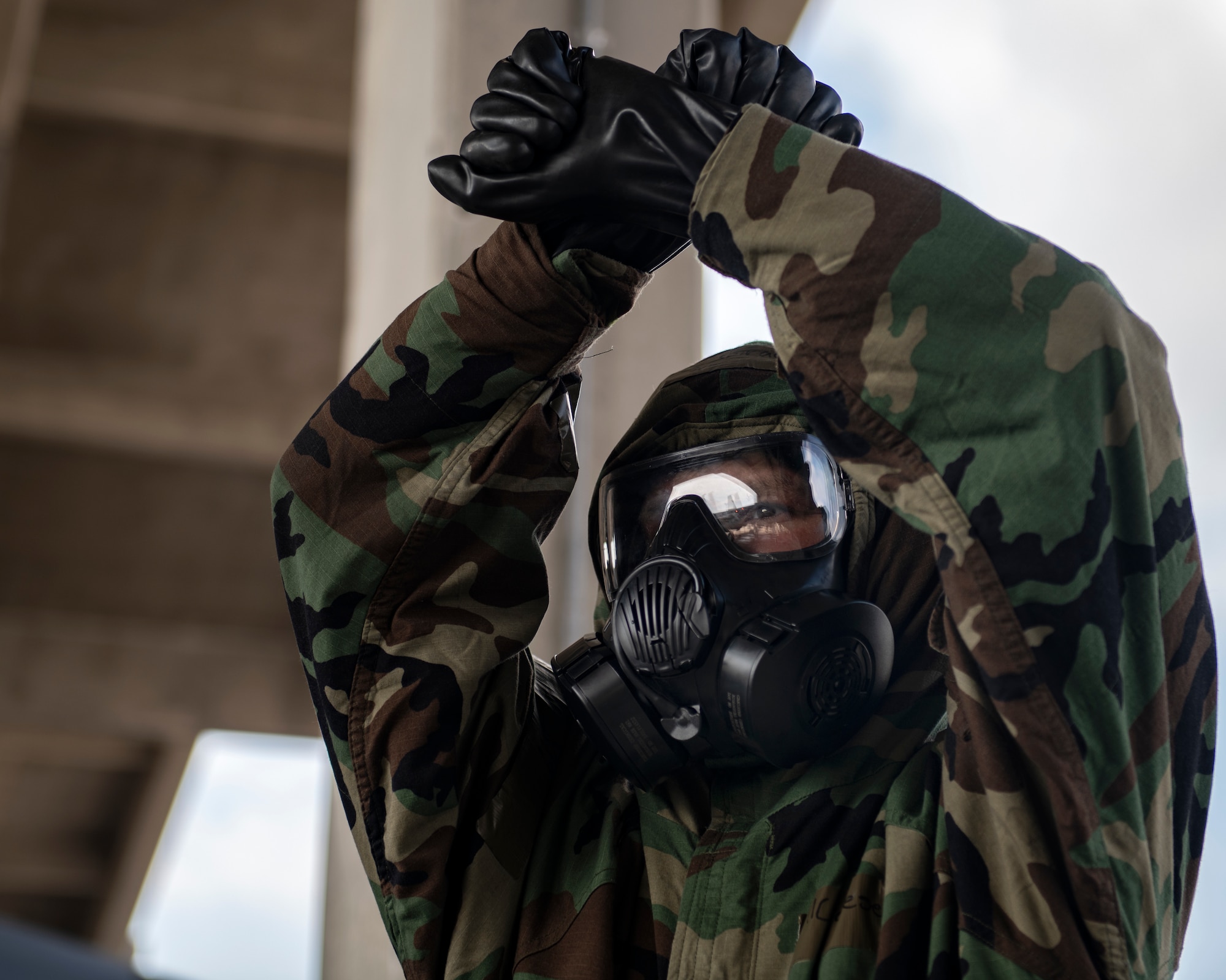 Airman 1st Class Samuel Graeser, 44th Aircraft Maintenance Unit crew chief, marshals an F-15C Eagle into the aircraft shelter during an ability to survive and operate training exercise at Kadena Air Base, Japan, Nov. 17, 2021. ATSO training ensures Airmen can effectively carry out their mission while wearing full Mission Oriented Protective Posture gear. (U.S. Air Force photo by Senior Airman Jessi Monte)