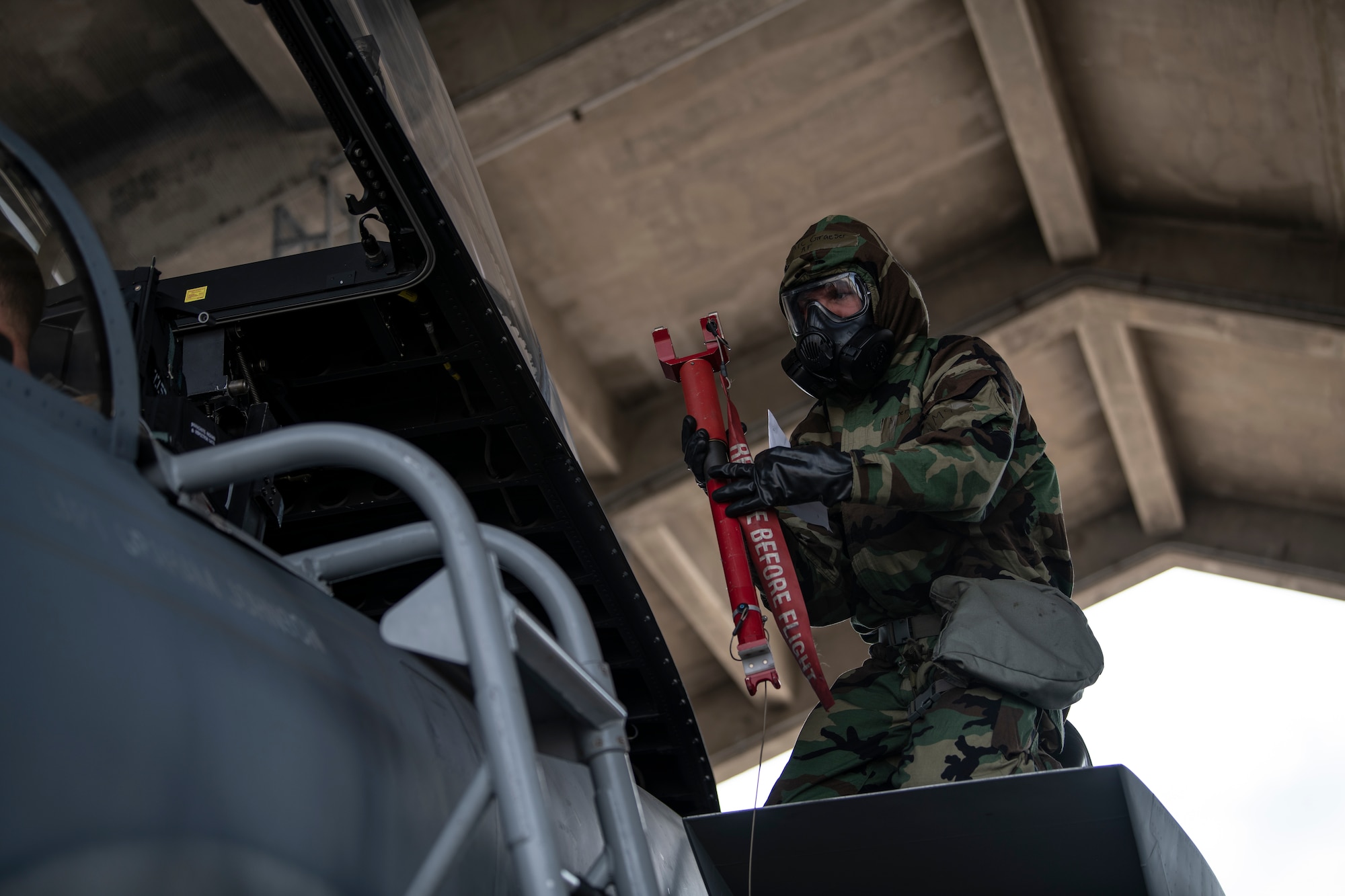 Airman 1st Class Samuel Graeser, 44th Aircraft Maintenance Unit crew chief, prepares to insert the canopy safety strut during an ability to survive and operate training exercise at Kadena Air Base, Japan, Nov. 17, 2021. ATSO training improves Airmens ability to quickly and accurately don Mission Oriented Protective Posture gear in the event of a chemical, biological, radiologic or nuclear threat. (U.S. Air Force photo by Senior Airman Jessi Monte)