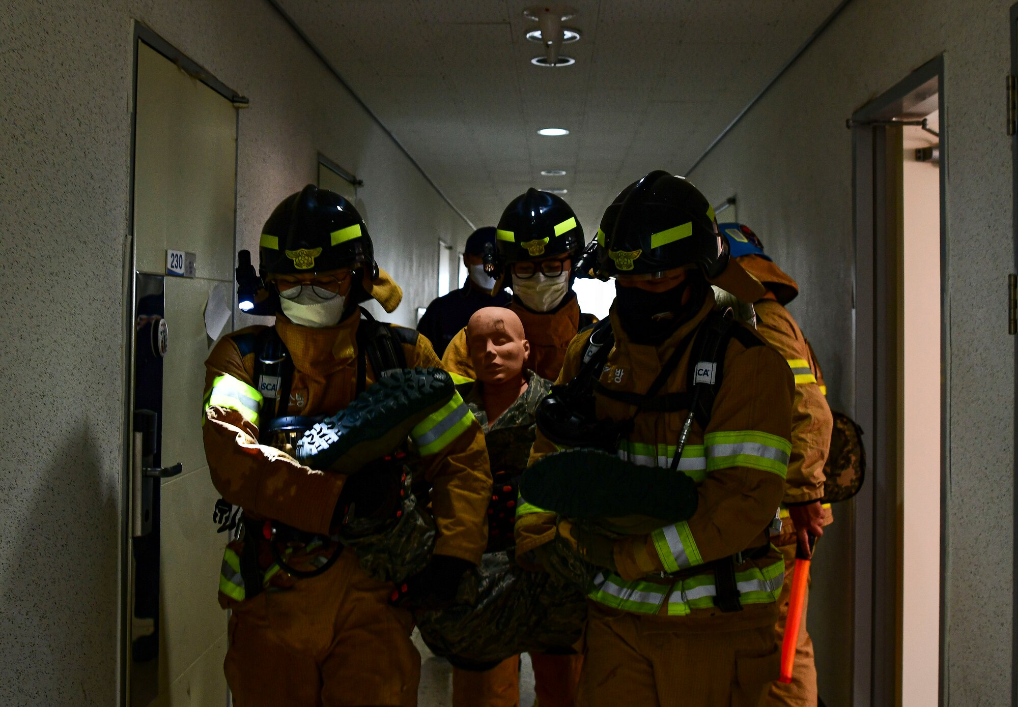 Airmen from the 8th Civil Engineer Squadron and 38th CES firefighter carry a dummy during a simulated structure fire at Kunsan Air Base, Republic of Korea, Nov. 4, 2021. Both 8th Fighter Wing and 38th Fighter Group firefighters were tested in their ability to respond quickly to a simulated structural fire on base. (U.S. Air Force photo by Staff Sgt. Jesenia Landaverde)