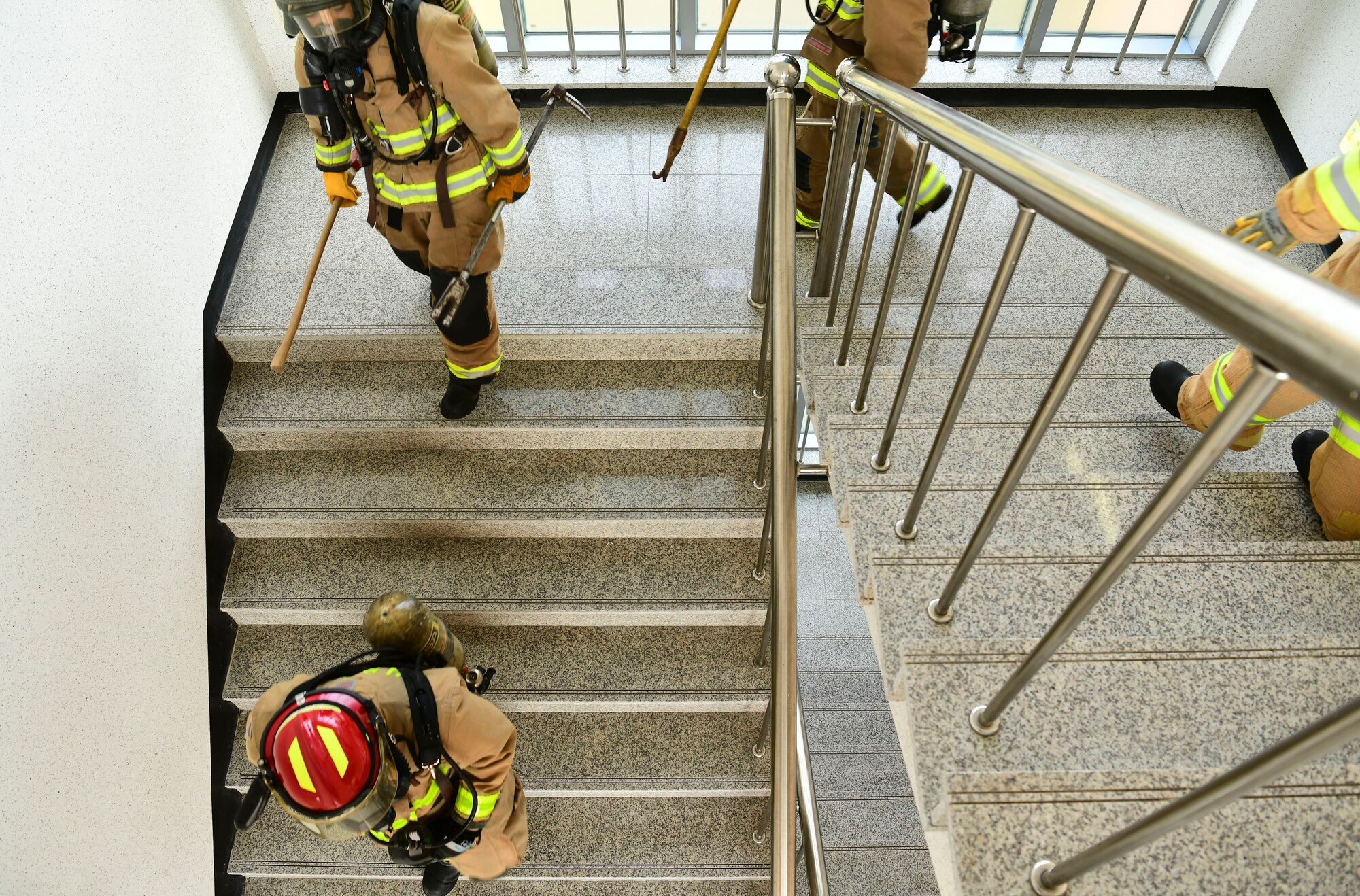 Airmen from the 8th Civil Engineer Squadron and 38th CES firefighter rush down the stairs during a simulated structure fire at Kunsan Air Base, Republic of Korea, Nov. 4, 2021. Both 8th Fighter Wing and 38th FW firefighters were tested in their ability to respond quickly to a simulated structural fire on base. (U.S. Air Force photo by Staff Sgt. Jesenia Landaverde)