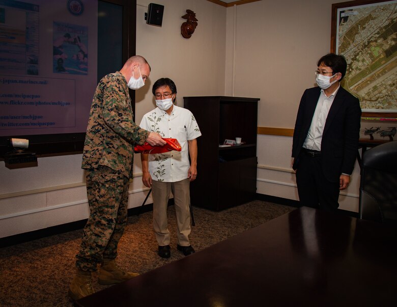 U.S. Marine Corps Col. Neil Owens, assistant chief of staff of government and external affairs (G-7), Marine Corps Installations Pacific, receives a gift during the Marine Corps 101 briefing at Marine Corp Air Station Futenma, Okinawa, Japan, on Nov. 18, 2021. Owens conducted a brief to inform business professionals from Global Tekijuku Business School on national security issues and the United States and Japan alliance. (U.S. Marine Corps photo by Sgt. Kayla V. Staten)