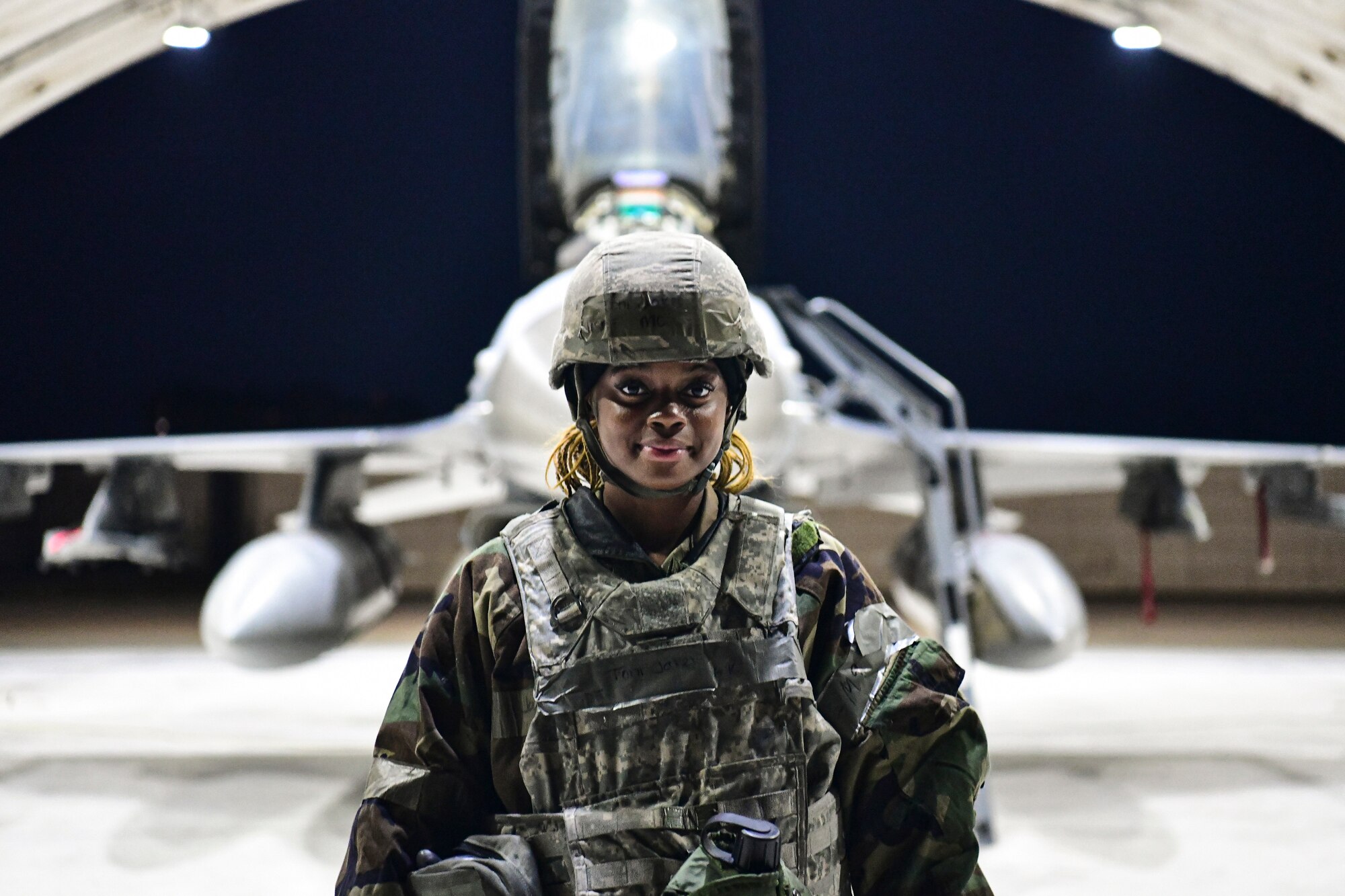 An Airman stands in front of an F-16.