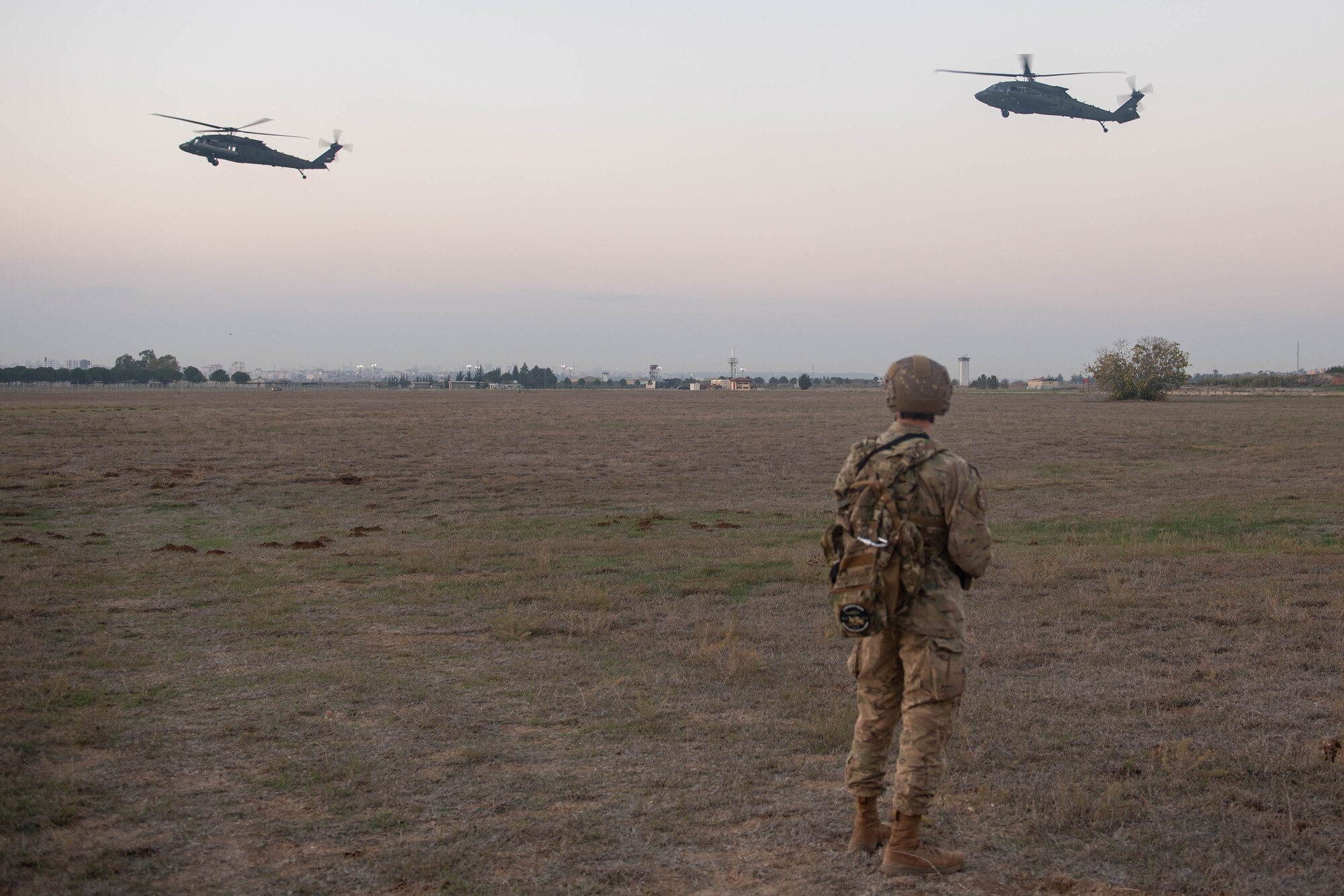A security forces member watches two UH-60 helicopters land during a joint training exercise