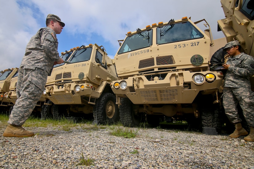 Troops stand near trucks.