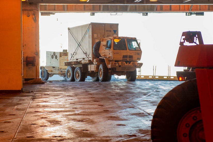 A truck rolls onto a ship.