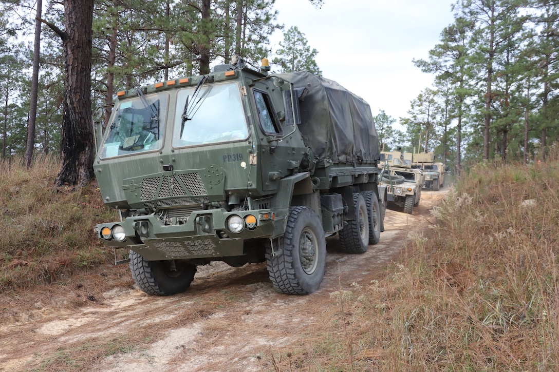 Trucks move down a dirt road.