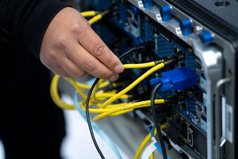 A hand plugs a cable into a port.