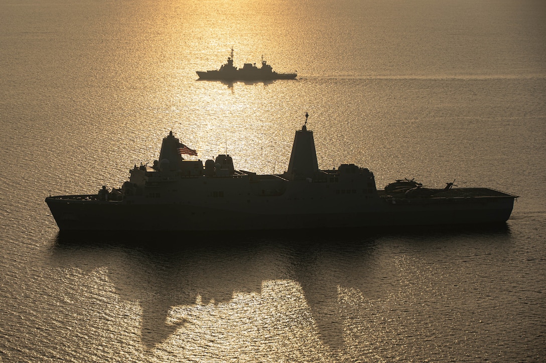 Two ships sail next to each other at twilight.