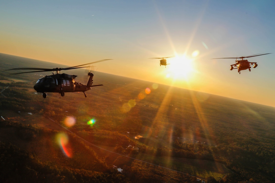 Three aircraft fly in silhouette amidst sunbursts.