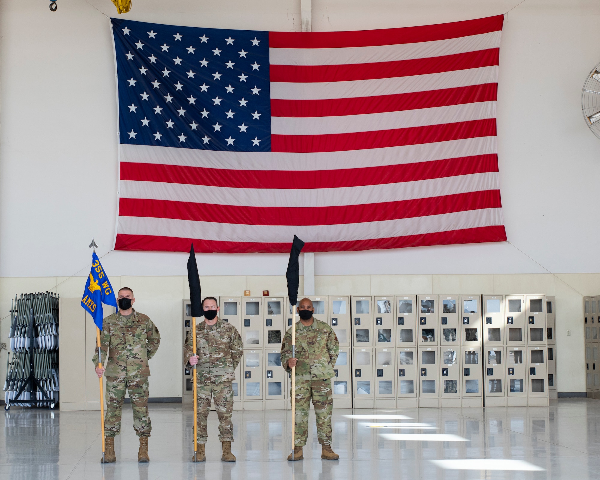 three men stand in front of a American flag.