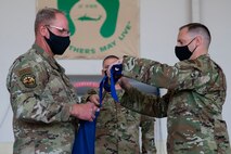 Two men roll up a guidon.