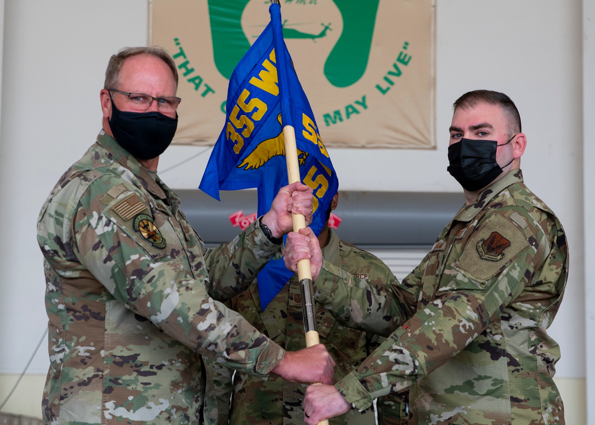 Two men pose holding a guidon.