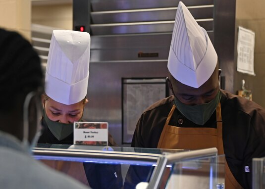 U.S. Air Force Chief Master Sgt. Rebecca Arbona, 17th Training Wing command chief, and Col. James Finlayson, 17th TRW vice commander, serve ham and turkey to a student during Thanksgiving at the Western Winds Dining Facility on Goodfellow Air Force Base, Texas, Nov. 25, 2021. Arbona and Finlayson asked each member about themselves and thanked them for their service. (U.S. Air Force photo by Senior Airman Ethan Sherwood)