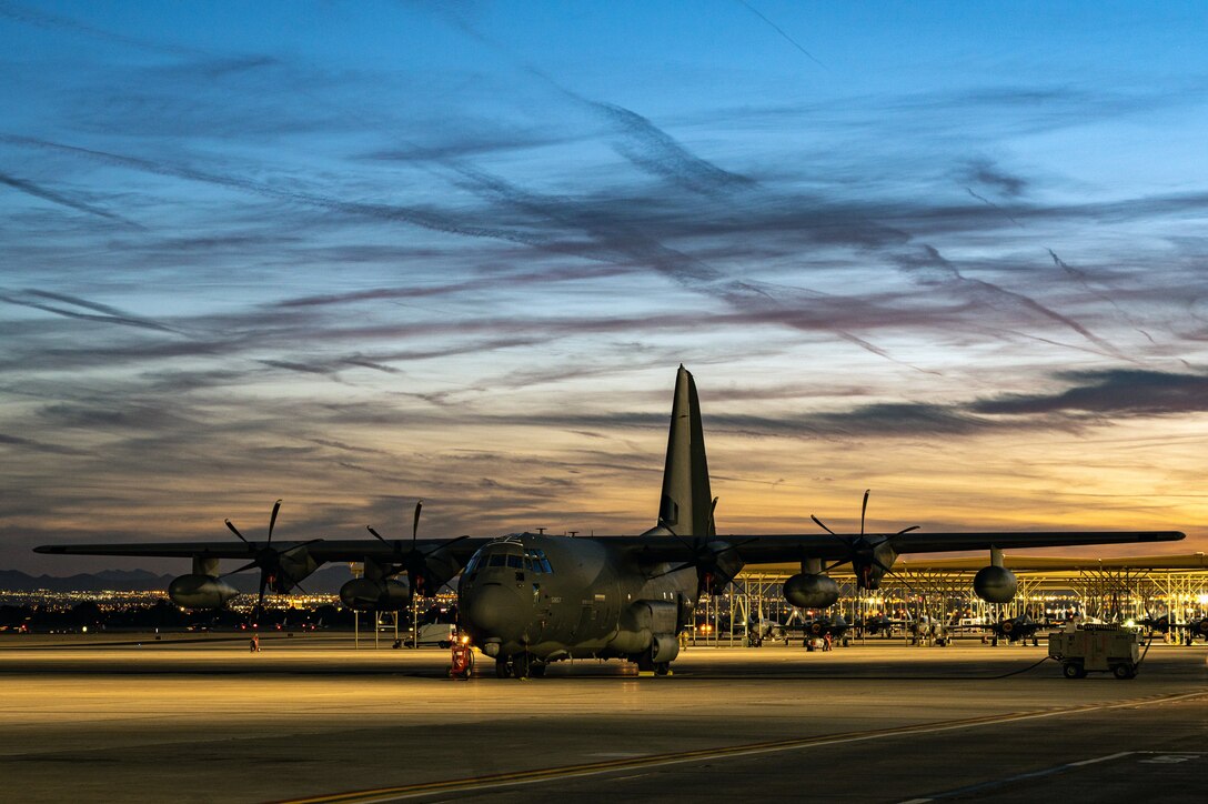 An HC-130J Combat King II sits on the flight line as the sun sets at Nellis Air Force Base
