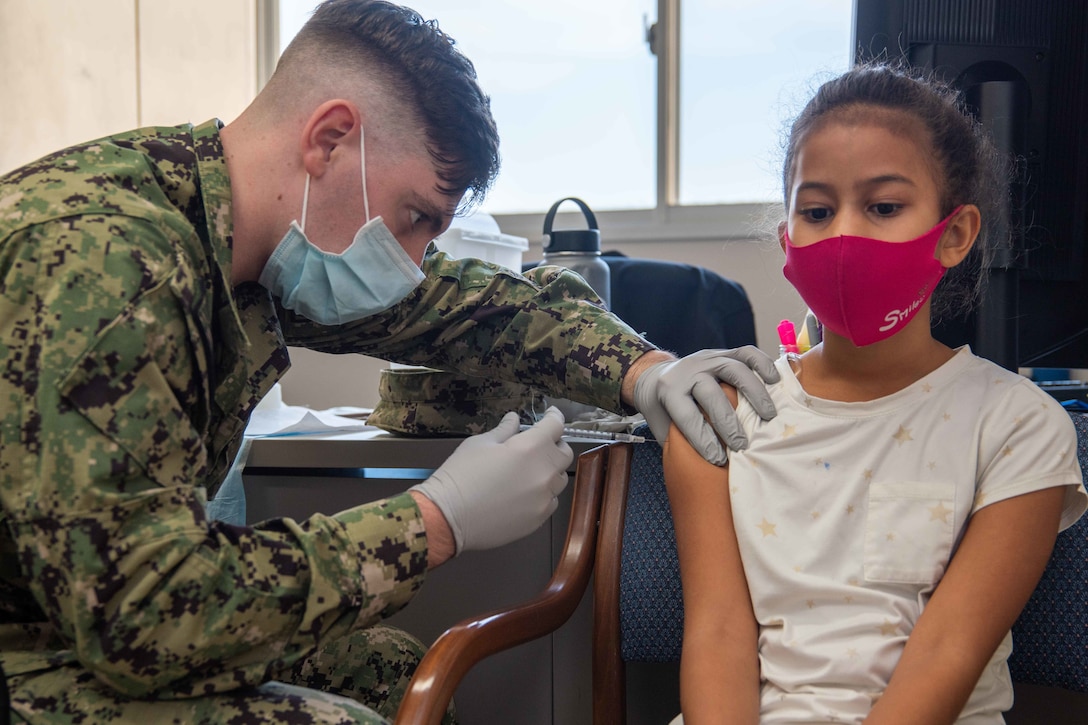 A sailor vaccinates a child.