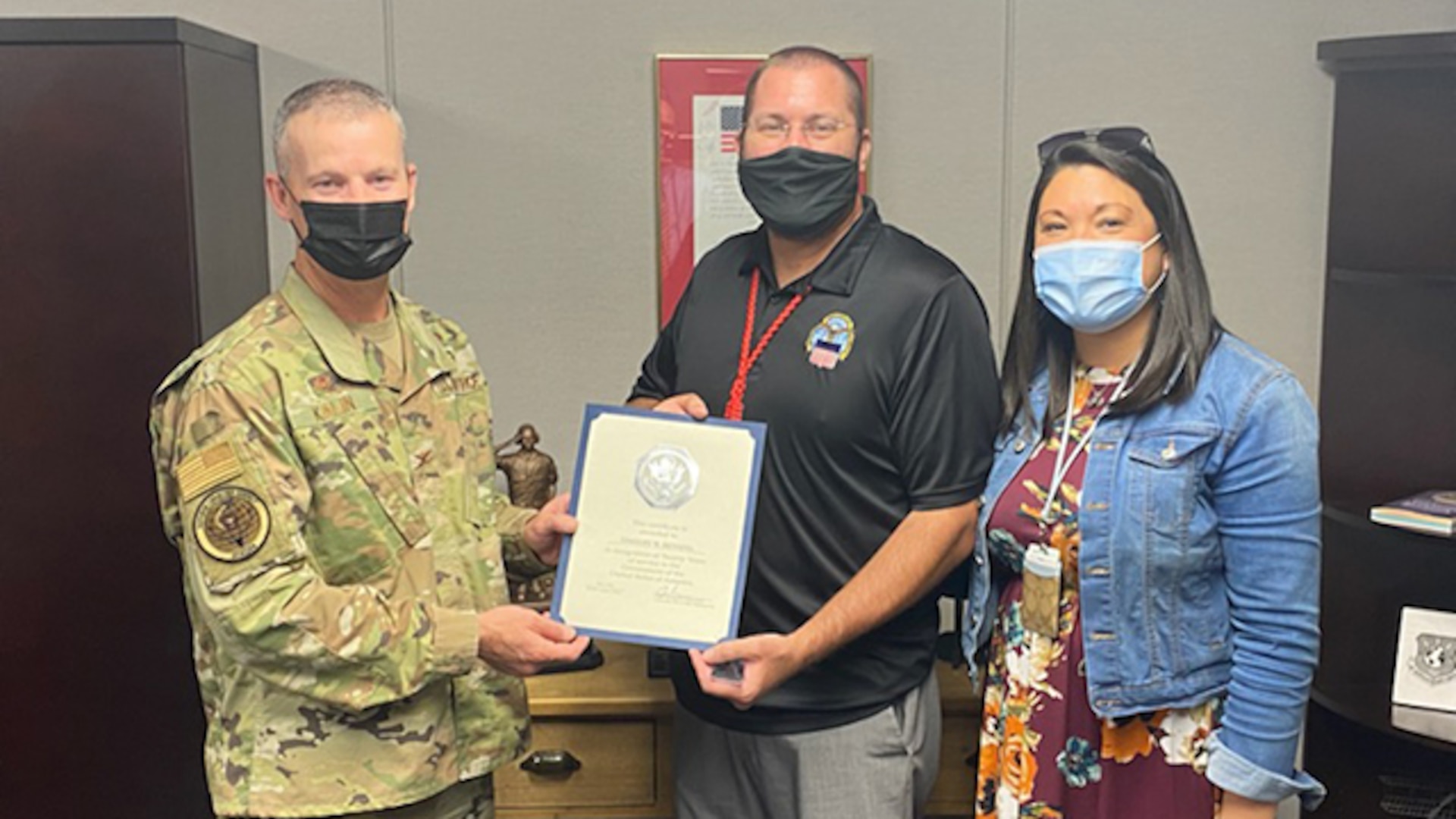 Col. Jason Kalin poses  with Timothy Henning and his wife Heather to present him with a certificate marking his 20 years of federal service.