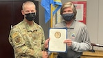 Col. Jason Kalin poses  with Randy Morningstar to present him with a certificate marking his 15 years of federal service.