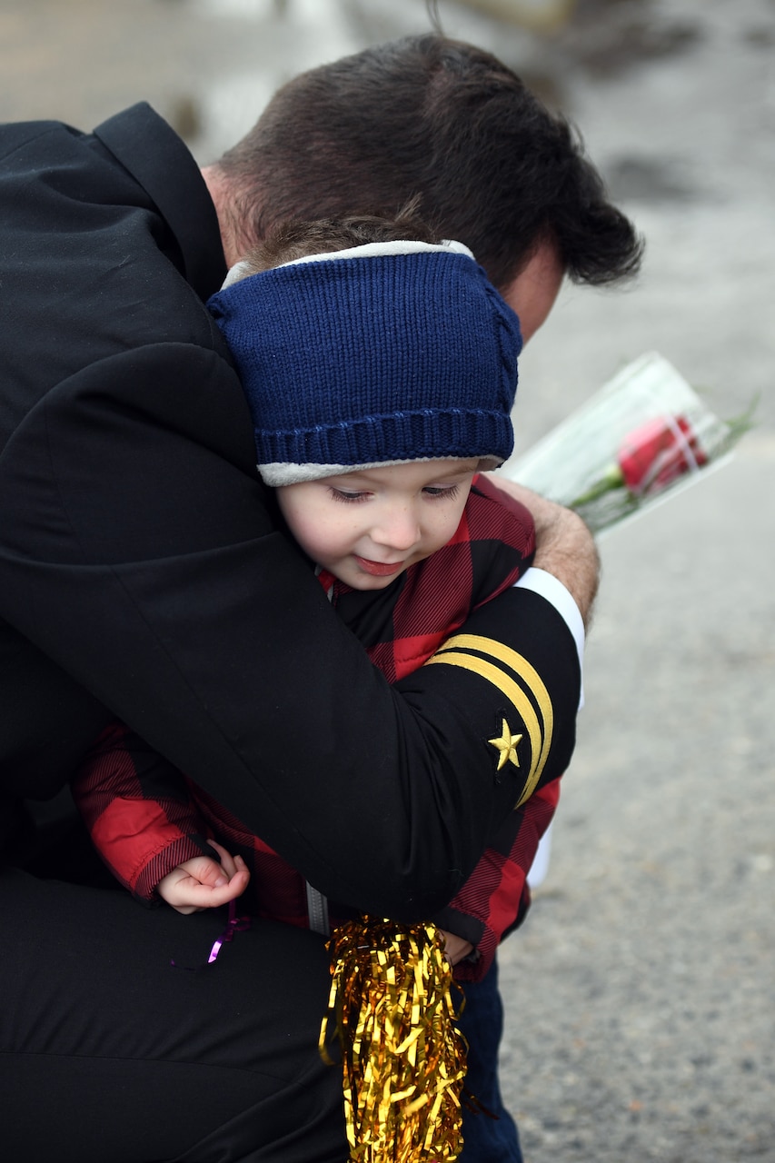 An officer attached to the Virginia-class submarine USS Minnesota (SSN 783) embraces his child during a homecoming event on board Naval Submarine Base New London in Groton, Conn., Nov. 26.