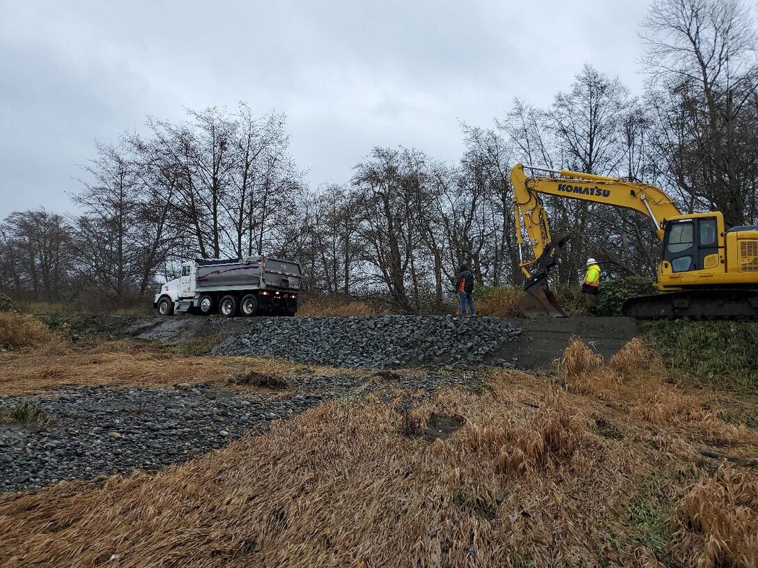 A construction dump truck and earth mover sit atop the repaired Rainbow Slough levee.