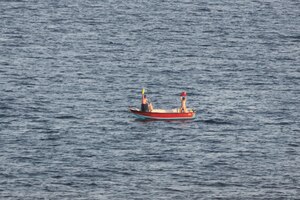 Two Iranian mariners signal for assistance Nov. 27 after their fishing vessel is adrift for eight days in the Gulf of Oman. Dry cargo ship USNS Charles Drew (T-AKE 10) responded and provided food, water and medical care.