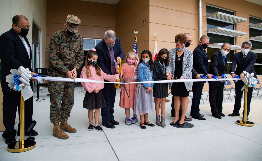 U.S. Marine Corps Col. Jeffery L. Hammond, commanding officer of Headquarters and Support Battalion, Marine Corps Installations Pacific, members of the school education board, officials from the local community, and students of Edward C. Killin Elementary School participate in the cutting of the ribbon during an official ribbon cutting ceremony of EC Killin Elementary on Camp Foster, Okinawa, Japan, Nov. 10, 2021. This commemoration celebrates a new opening of a replacement building with a 21st century design to promote the demands of new education learning for the incoming students. (U.S. Marine Corps photo by Cpl. Faith Rose)