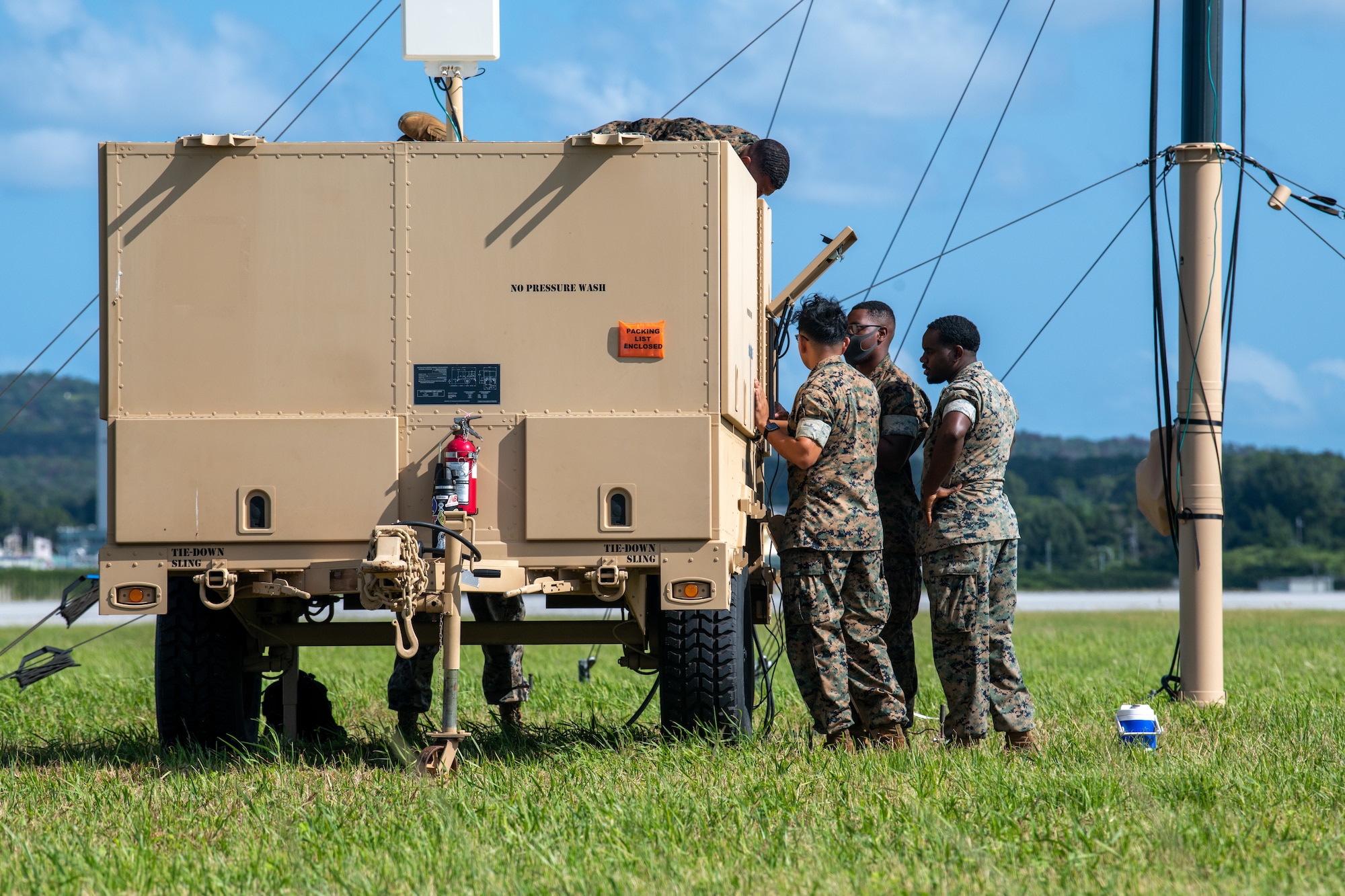 Marines stand to the right of a machine on wheels