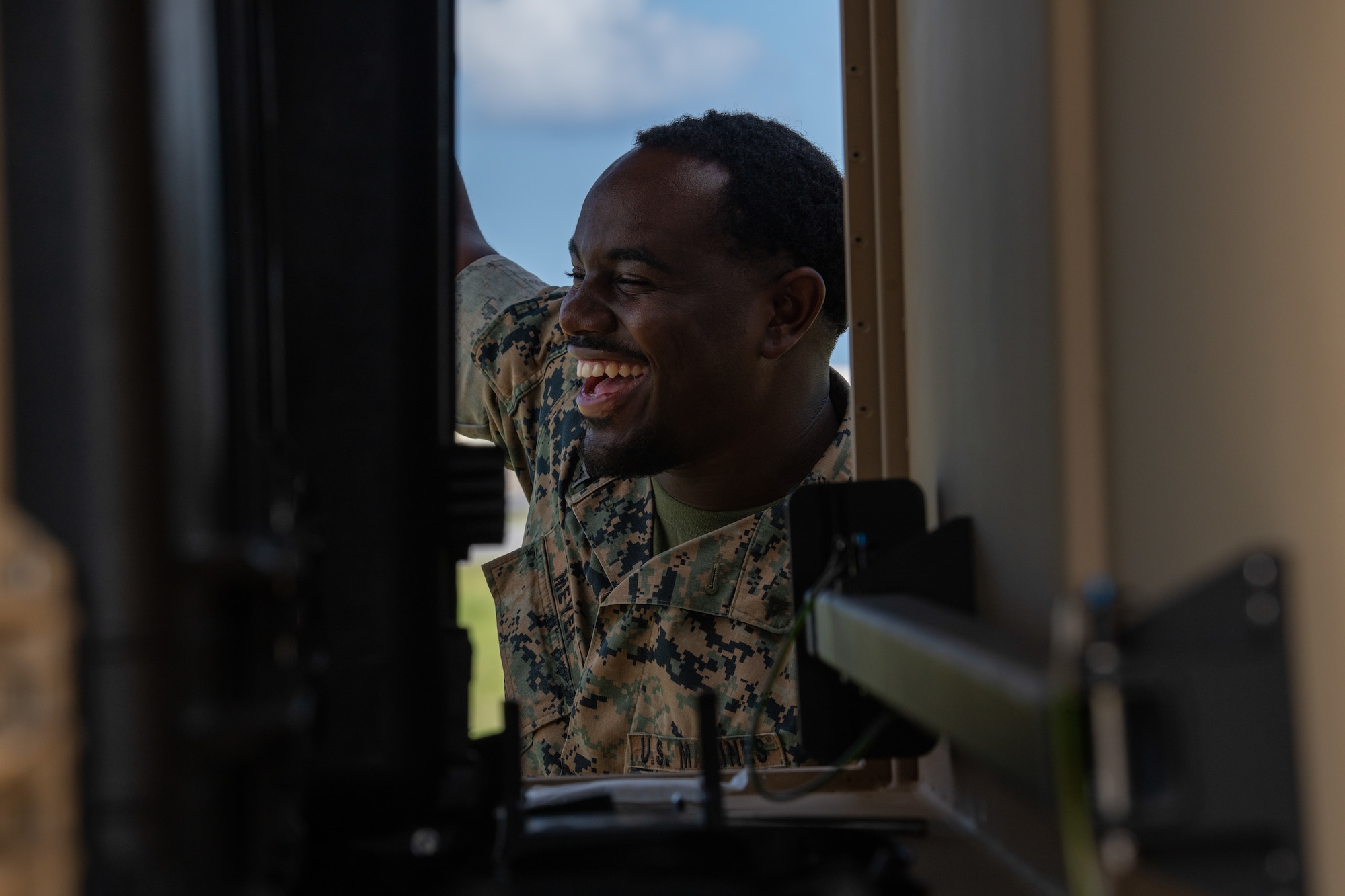 A marine laughs in between the sides of a machine