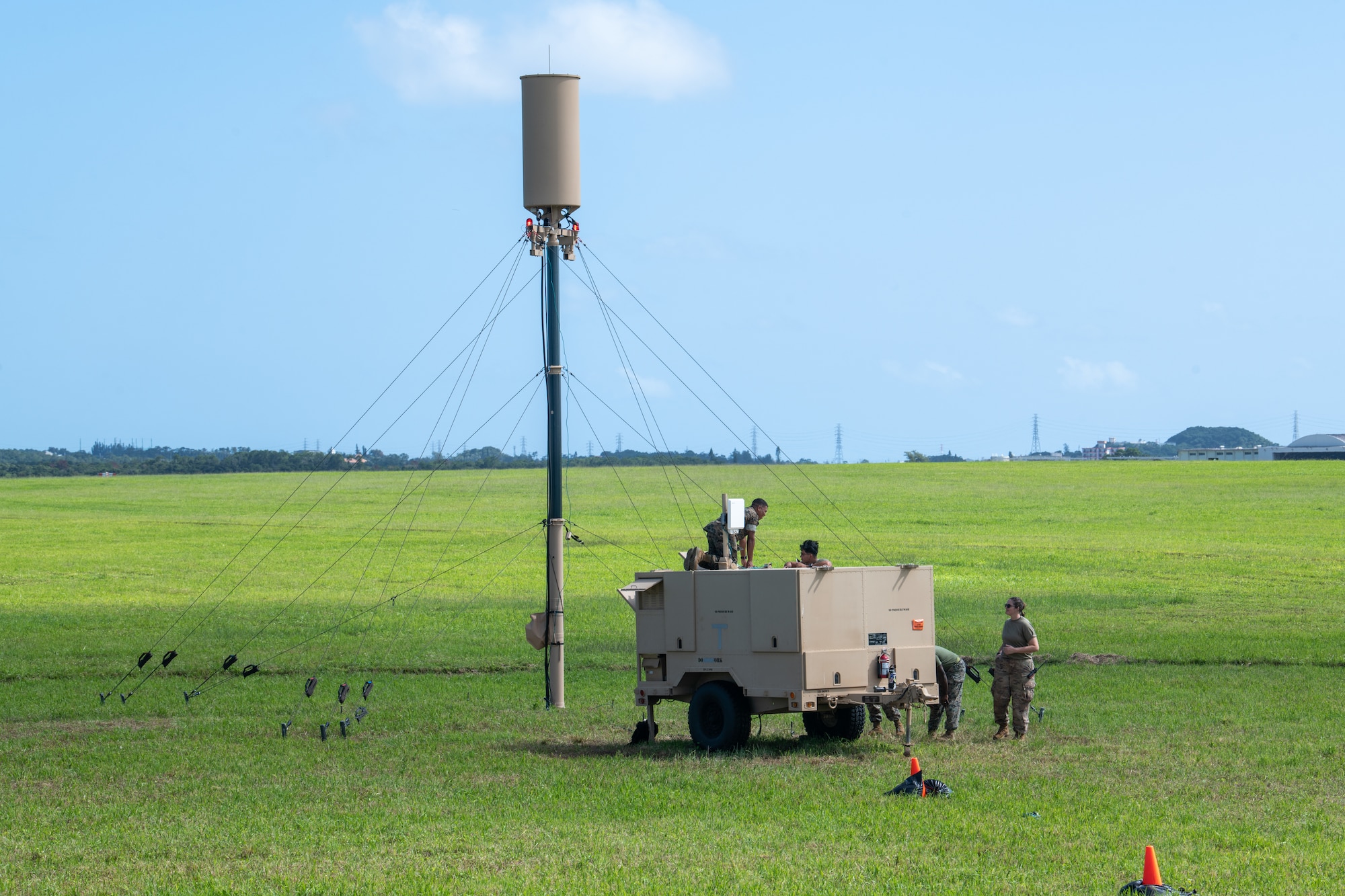 Some marines stand around a machine on wheels next to a radar tower.