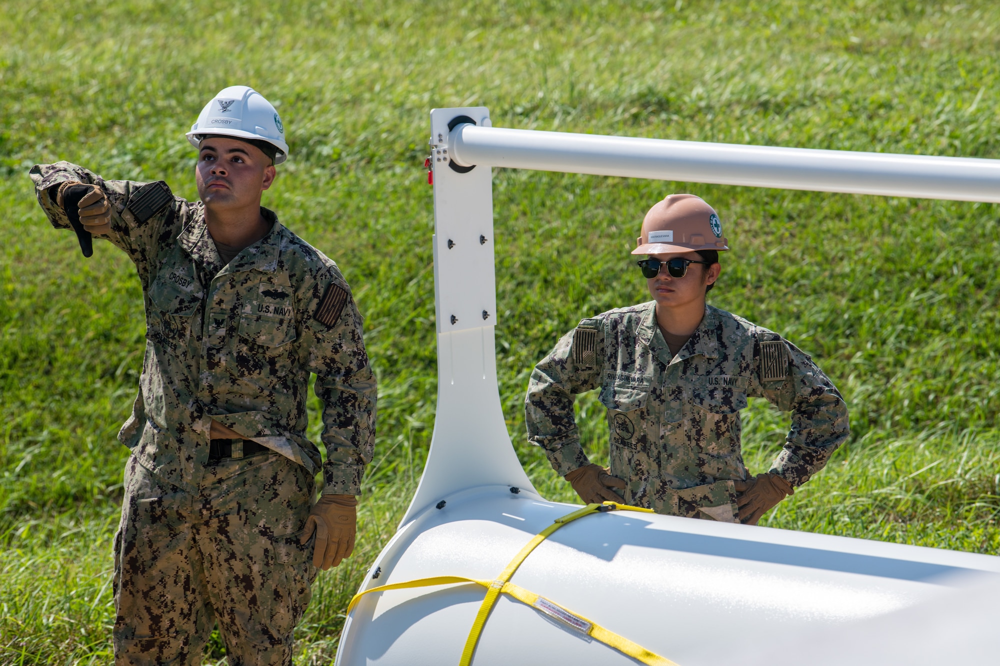 A male and female sailor give directions to a crane