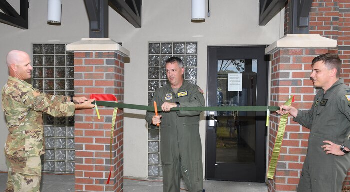 U.S. Air Force Col. Robert Lankford, 437th Airlift Wing commander cuts the ceremonial ribbon held by U.S. Air Force Lt. Col. Alexander Pelbath, 437th Operations Group director of C-17 Special Operations and U.S. Air Force. Capt. Charles Lambert, 15th Airlift Squadron C-17 Globemaster III pilot during the reopening of the 437th AW alert dorms at Joint Base Charleston, South Carolina, Oct. 22, 2021.