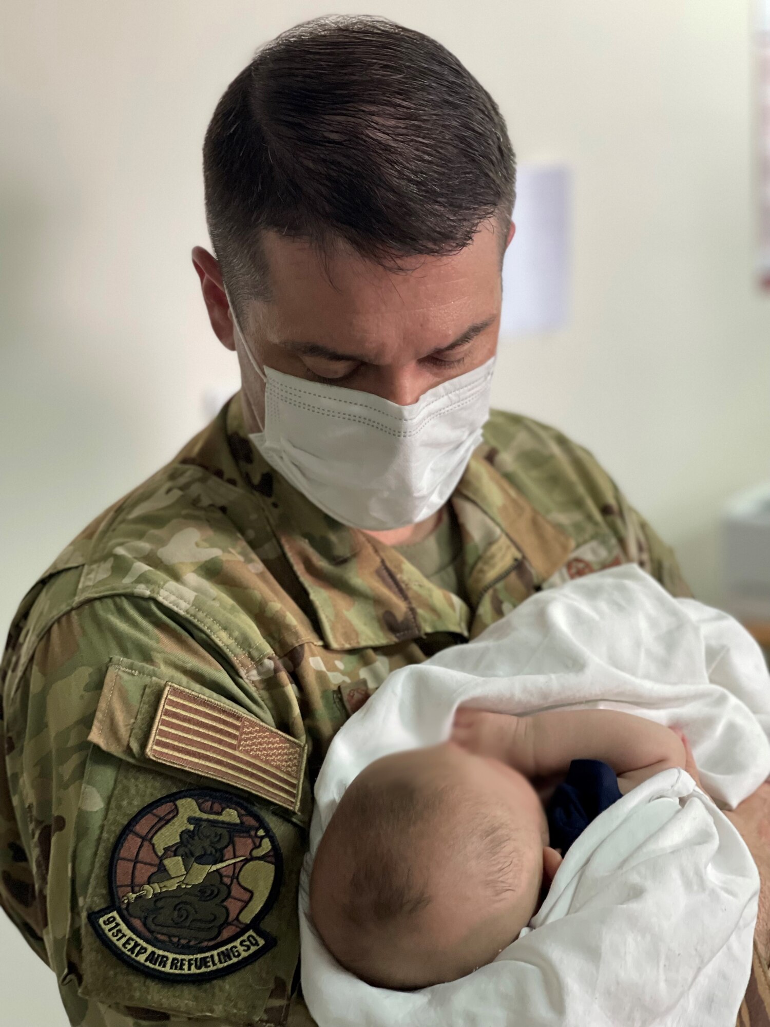 U.S. Air Force Lt. Col. Ivan Blackwell, 91st Air Refueling Squadron (ARS) holds a baby while on a deployment to Al Udeid Air Base, Qatar.