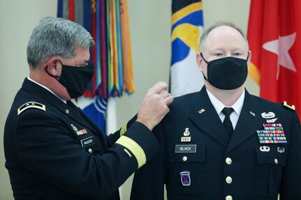 Retired Maj. Gen. Mark McQueen, former commanding general, 108th Training Command (IET), replaces the one-star shoulder boards with two-star shoulder boards during the promotion ceremony of Maj. Gen. Mark E. Black, director of operations, J3 (Wartime) United States Forces Korea. The ceremony took place November 16, 2021, at the Joint Atrium, Marshall Hall, Fort Bragg, N.C.