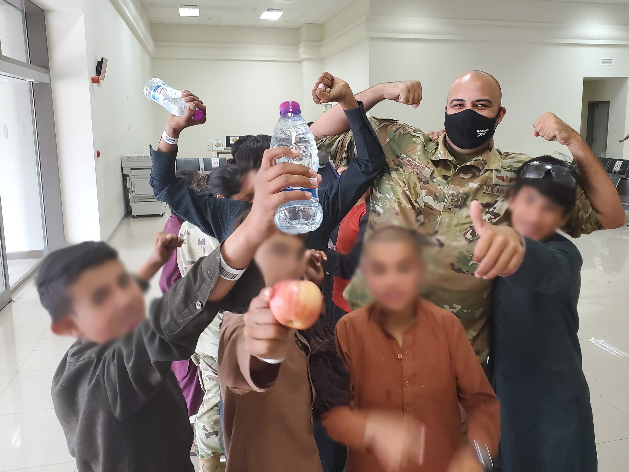 U.S. Air Force Tech. Sgt. Michael Eiland, a boom operator assigned to the 91st Air Refueling Squadron and children from Afghanistan pose for a photo, Aug. 26, 2021, at Al Udeid Air Base, Qatar.