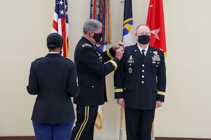 Retired Maj. Gen. Mark McQueen, former commanding general, 108th Training Command (IET), replaces the one-star shoulder boards with two-star shoulder boards during the promotion ceremony of Maj. Gen. Mark E. Black, director of operations, J3 (Wartime) United States Forces Korea. The ceremony took place November 16, 2021, at the Joint Atrium, Marshall Hall, Fort Bragg, N.C.