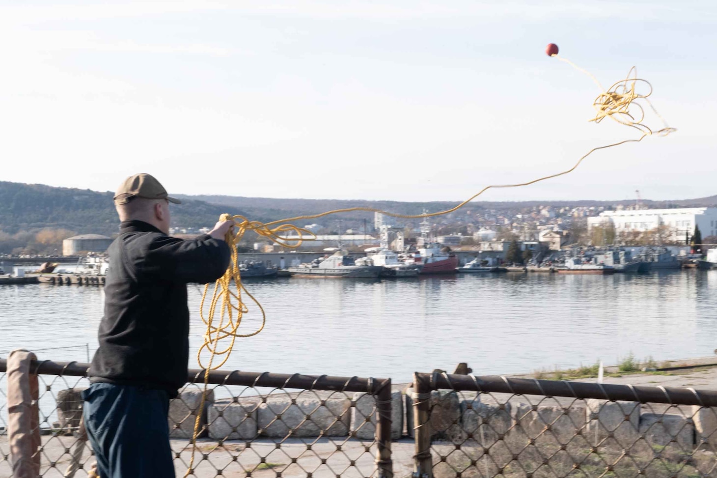 Fire Controlman (Aegis) 2nd Class Richard Shelley throws a line from the Arleigh Burke-class guided-missile destroyer USS Arleigh Burke (DDG 51) to the pier while mooring in Varna, Bulgaria, Nov. 26, 2021. Arleigh Burke, forward-deployed to Rota, Spain, is on its first patrol in the U.S. Sixth Fleet area of operations in support of U.S. National Security Interests and regional allies and partners.