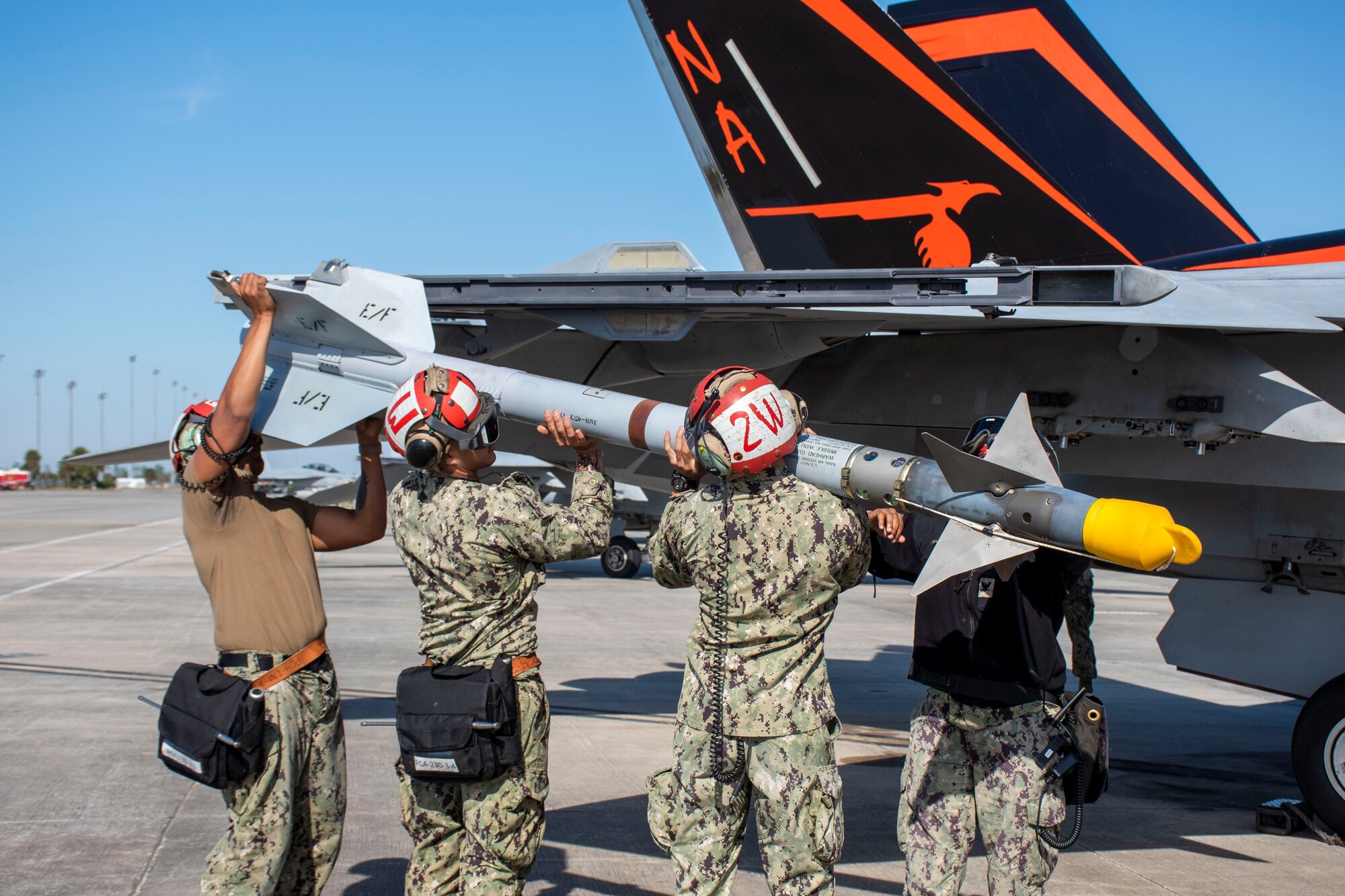 Four Ordnancemen attached to Strike Fighter Squadron 94 load an AIM-9 Sidewinder onto the wingtip launcher of an F/A-18F Super Hornet before a live-fire mission at Tyndall AFB, Fla., Nov. 10, 2021. WSEP tests and validates the performance of crews, pilots, and their technology to enhance readiness for real-world operations. (U.S. Air Force photo by 1st Lt Lindsey Heflin)