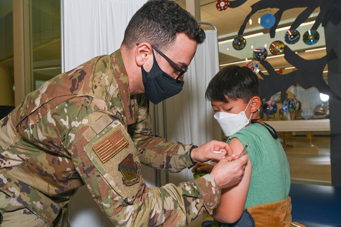 An airman puts a bandage on a child's arm after vaccination.