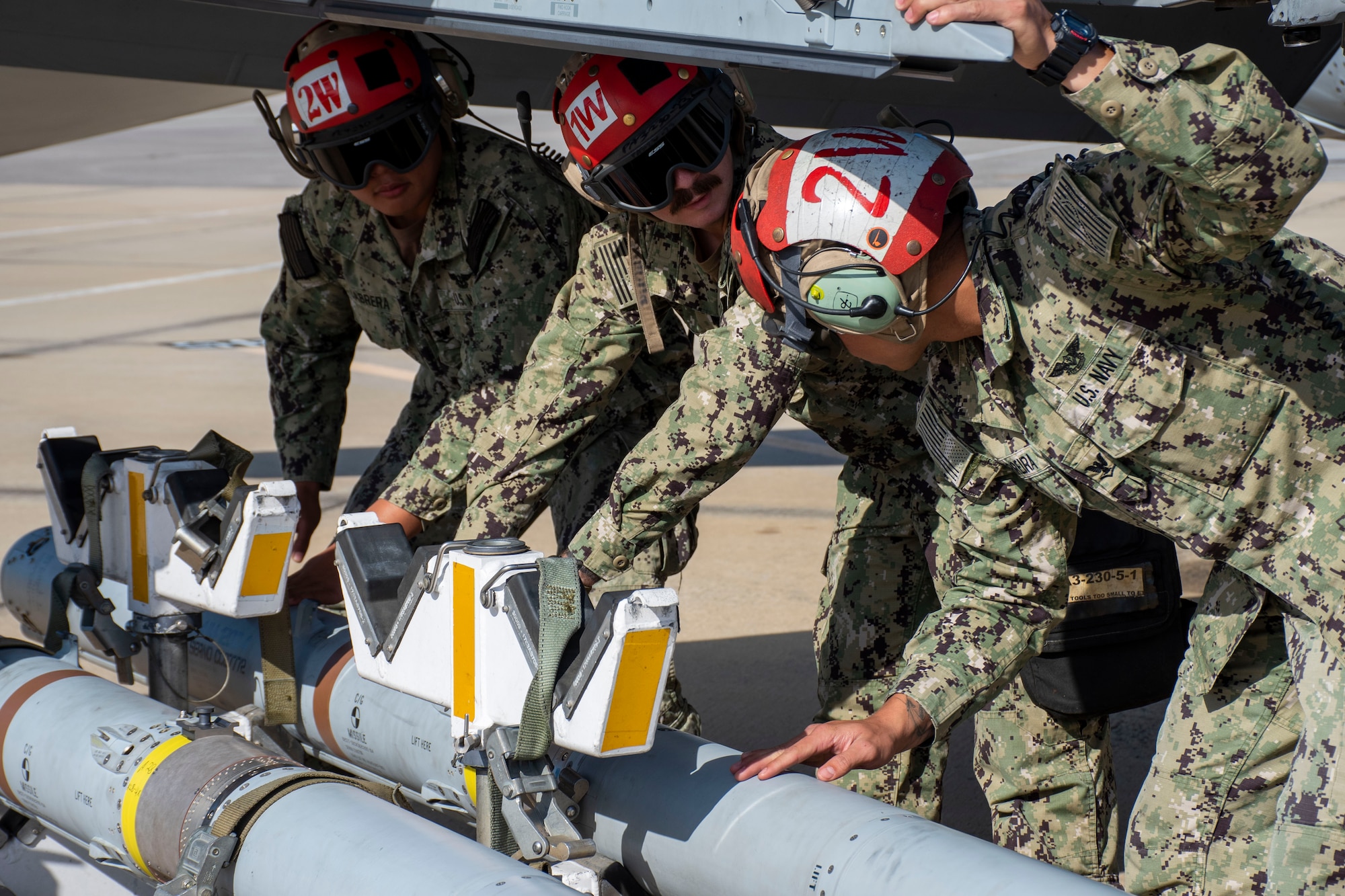 Three Aviation Ordnancemen attached to Carrier Air Wing 17 prepare to load an AIM-120 AMRAAM before a live-fire mission at Tyndall AFB, Fla., Nov. 10, 2021. WSEP tests and validates the performance of crews, pilots, and their technology to enhance readiness for real-world operations. (U.S. Air Force photo by 1st Lt Lindsey Heflin)