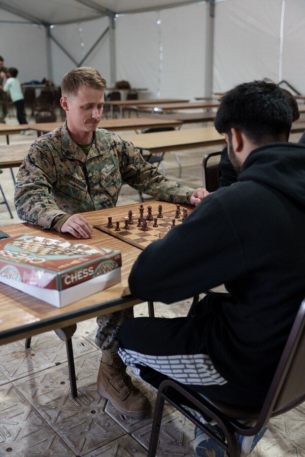 U.S. Navy Petty Officer 2nd Class Sean Richardson, religious program specialist, 26th Marine Expeditionary Unit, plays chess with an Afghan evacuee on Fort Pickett, Virginia, Nov. 19, 2021. The event is part of a variety of activities available to Afghan individuals as they await the next steps in their resettlement process. Task Force Pickett personnel joined the tournament to develop friendships in a competitive environment. The Department of Defense, through U.S. Northern Command, and in support of the Department of Homeland Security, is providing transportation, temporary housing, medical screening, and general support for at least 50,000 Afghan evacuees at suitable facilities, in permanent or temporary structures, as quickly as possible. This initiative provides Afghan personnel essential support at secure locations outside Afghanistan. (U.S. Marine Corps photo by Sgt. Corey Mathews)