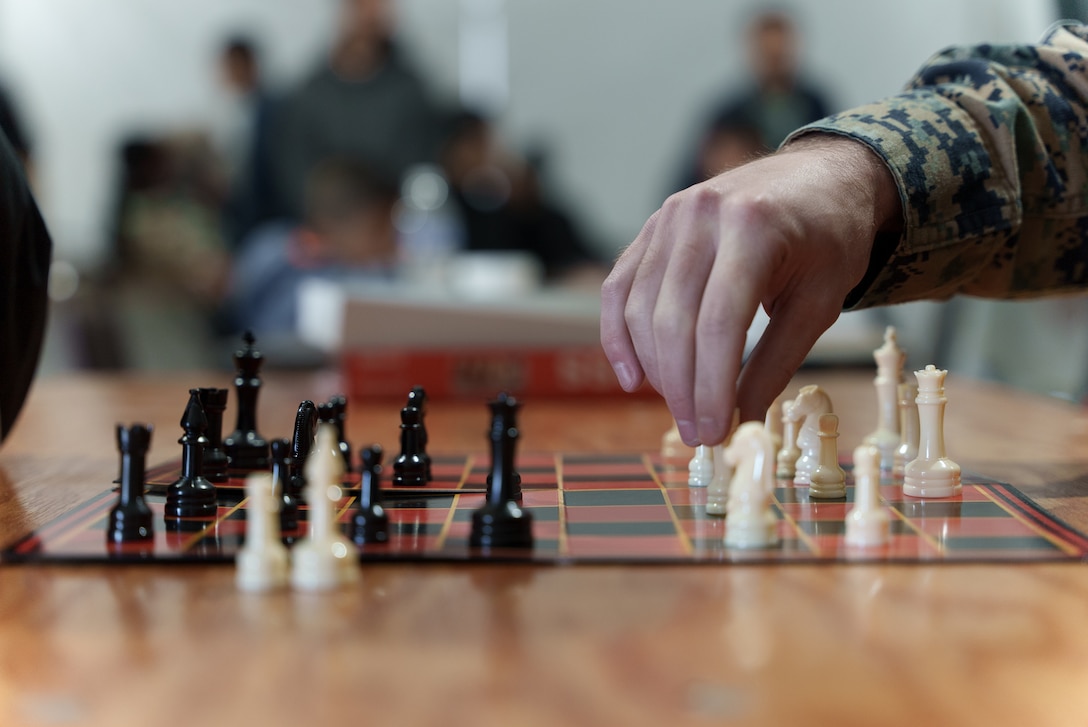 U.S. Marine Corps 1st Lt. Jacob Sugg, deputy director, Communication Strategy and Operations, 26th Marine Expeditionary Unit, plays chess with an Afghan evacuee on Fort Pickett, Virginia, Nov. 19, 2021.